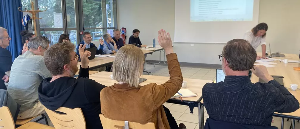 Trois personnes lèvent la main pour effectuer un vote